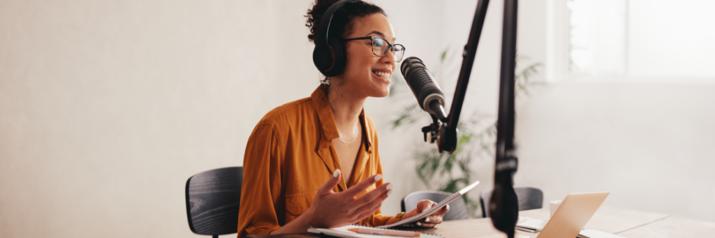 Woman recording a podcast or conducting an online conversation using a microphone and headphones.